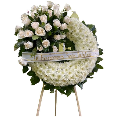 White wreath filled with pompom cushion, with a bouquet on the side filled with white roses, eucalyptus and lemon leaf around it